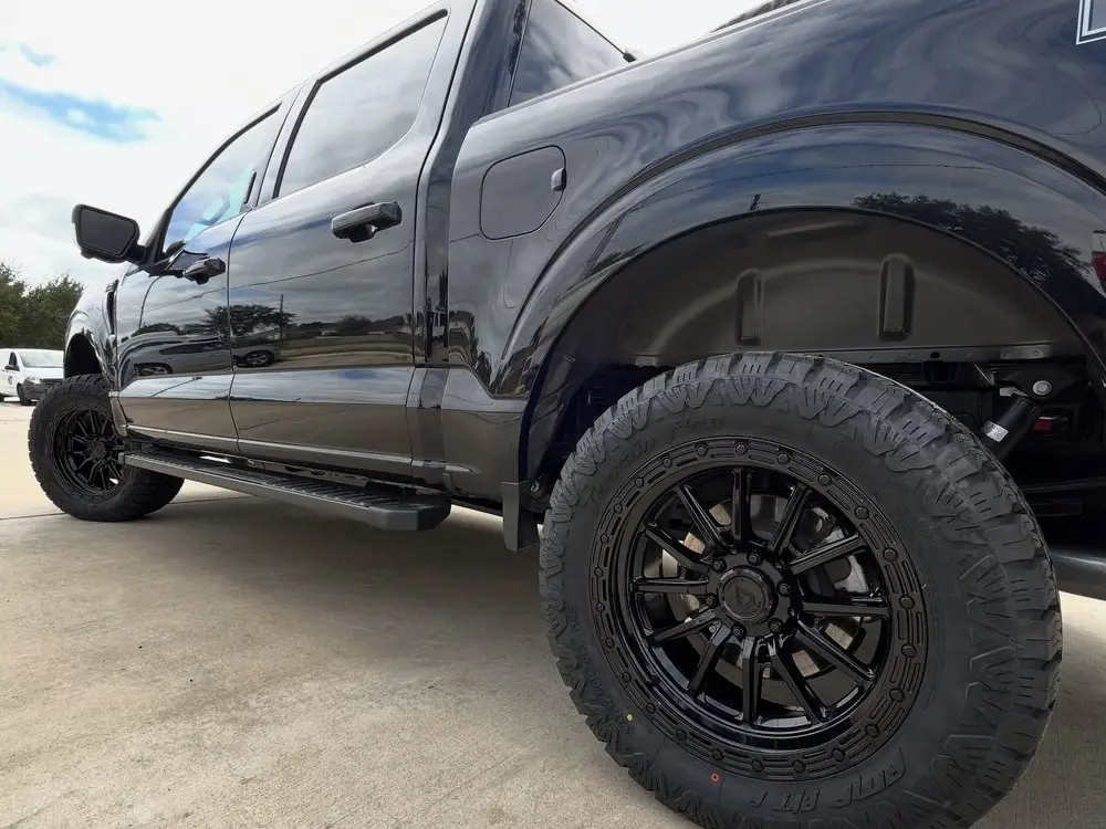 Black Ford F-150 on gloss black wheels and aggressive all-terrain tires