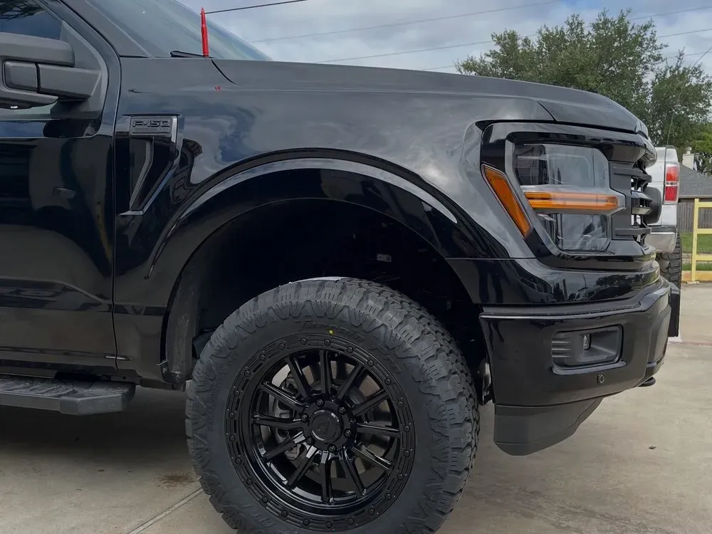 Leveled black Ford F-150 on black aftermarket wheels and all-terrain tires