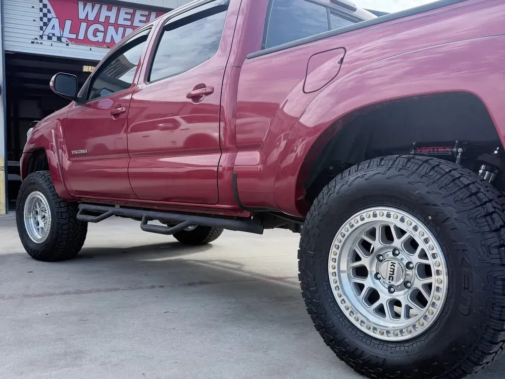 Lifted red Toyota Tacoma with new suspension, silver wheels and all-terrain tires