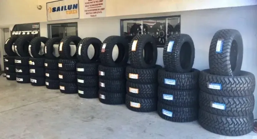 Rows of new off-road truck tires stacked inside the tire shop showroom