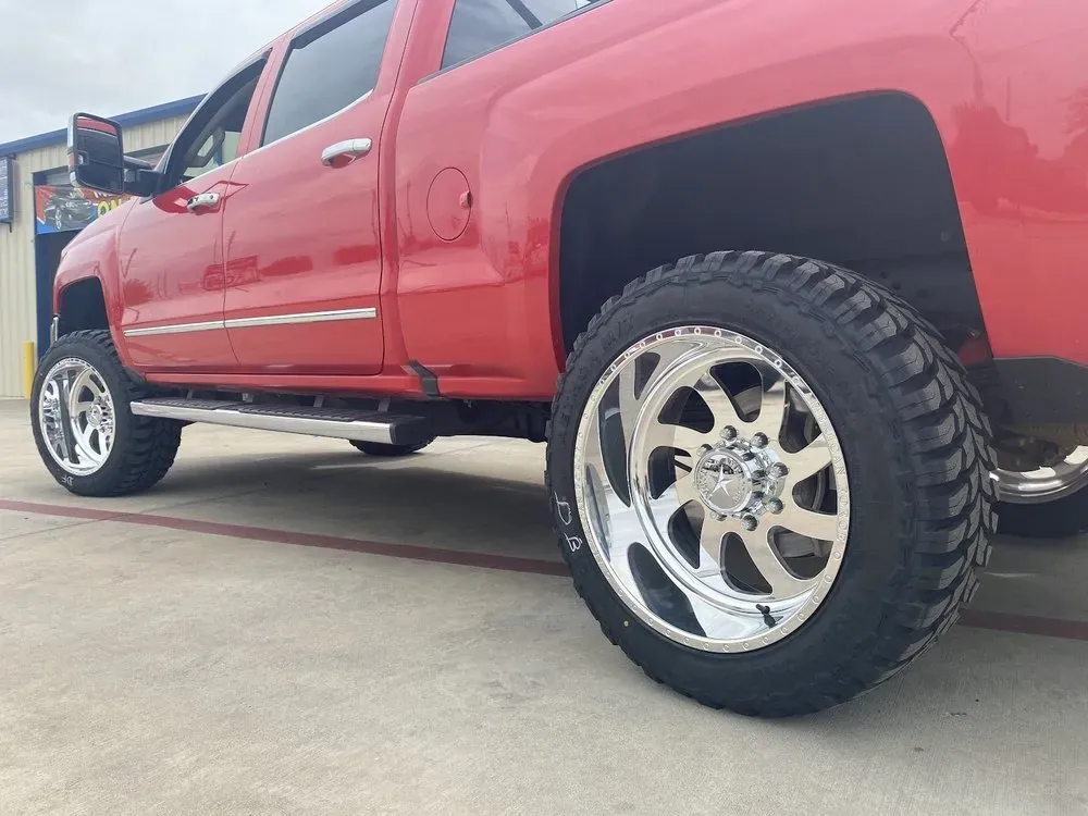 Red Chevrolet Silverado on polished forged-style wheels with off-road tires