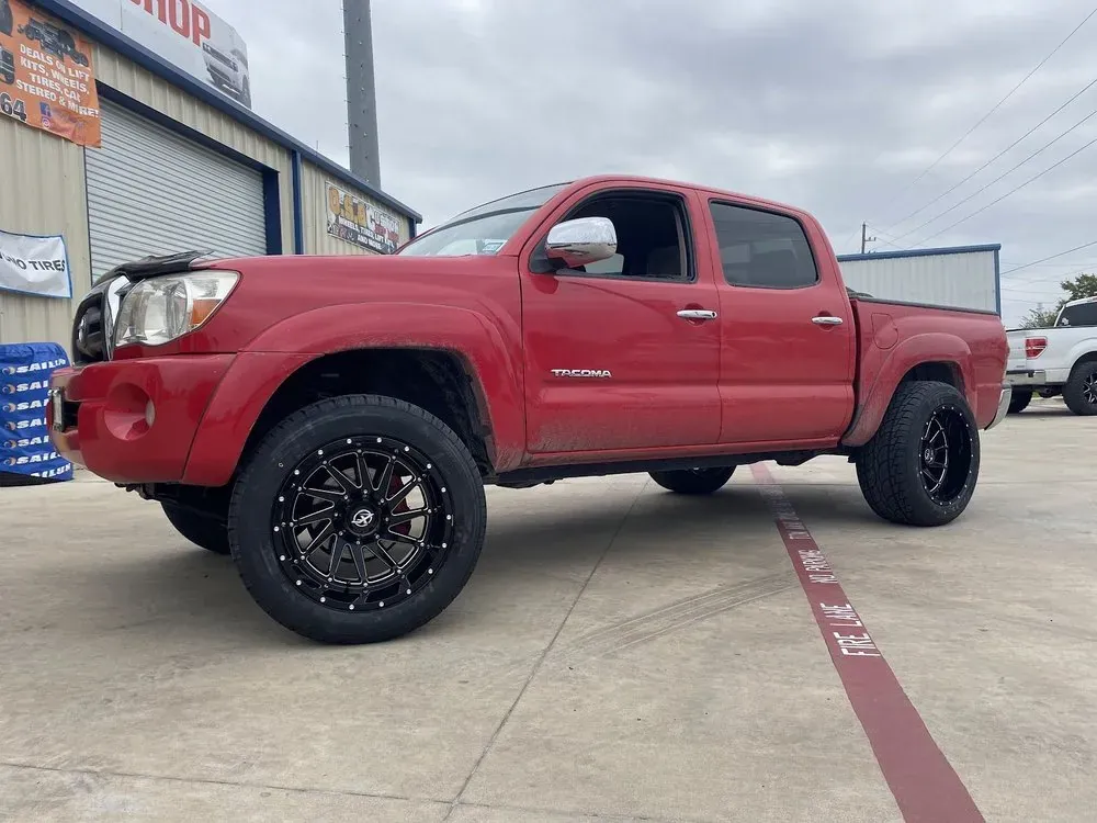 Red Toyota Tacoma on black and machined aftermarket wheels with all-terrain tires